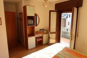 a bedroom with a bed and a television and a balcony at Albergo Ristorante Sciatori in Pievepelago