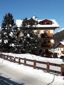 a building with a fence and trees in the snow at Casa Vacanze Michela in Santa Caterina Valfurva +56 photos
