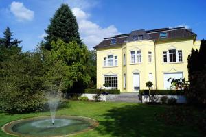 a large yellow house with a fountain in the yard at Hotel Villa Wittstock in Burg