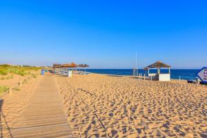 a sandy beach with a wooden boardwalk and umbrellas at Bayside Salgados in Albufeira