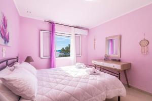 a pink bedroom with a bed and a window at Alkinoi Seaview Villa with Private Pool by Konnect, Nisaki in Nisakion