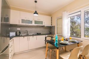 a kitchen with white cabinets and a table with chairs at Alkinoi Seaview Villa with Private Pool by Konnect, Nisaki in Nisakion