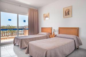 two beds in a hotel room with a balcony at Apartamentos Es Cañe in Es Cana