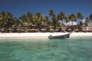 ein Boot im Wasser vor einem Strand in der Unterkunft Constance Sakoa Boutik in Trou aux Biches