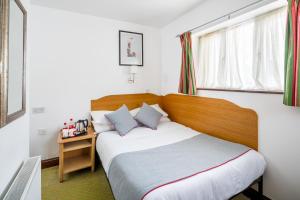 a bedroom with a bed with a wooden headboard at OYO Abbey Hotel, London Shepherd's Bush Market in London