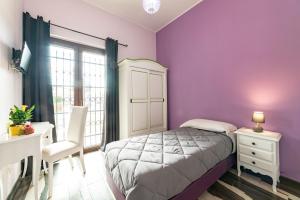 a bedroom with purple walls and a bed and a desk at Myricae Rooms Affittacamere in Fiumicino