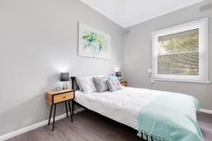 a white bedroom with a bed and a window at Cute and Cosy - events, workers, getaways in Murray Bridge
