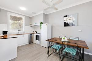 a white kitchen with a wooden table and chairs at Cute and Cosy - events, workers, getaways in Murray Bridge