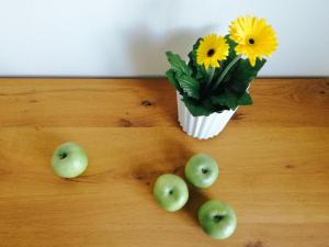 un mucchio di mele verdi e un vaso con fiori gialli di Garda Rooms a Desenzano del Garda