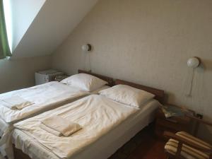 a bed with white sheets and pillows in a room at Koller Panzió in Bonyhád