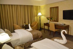 Una habitación de hotel con dos camas con cisnes. en Saray Hotel Amman en Amán
