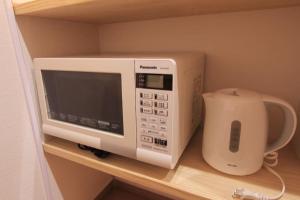 a microwave sitting on a shelf in a kitchen at NY Stage 新宿 in Tokyo