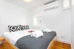 ein weißes Schlafzimmer mit einem Bett mit Handtüchern darauf in der Unterkunft Cosy Alfama Hideout - with rooftop terrace in Lissabon
