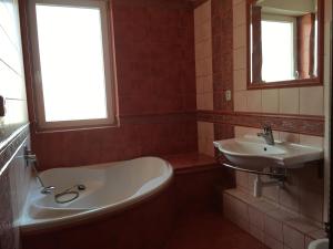 ein Bad mit einer Badewanne, einem Waschbecken und einem Fenster in der Unterkunft Spacious Apartment in Town Centre in Nové Zámky