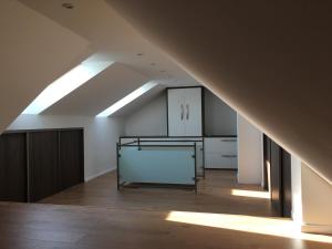 uma cozinha no sótão com armários brancos e uma clarabóia em Spacious Apartment in Town Centre em Nové Zámky