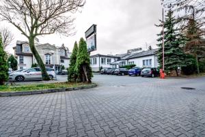 un aparcamiento con coches estacionados frente a las casas en Wzgórze Toskanii Conferences & Restaurant, en Przeźmierowo