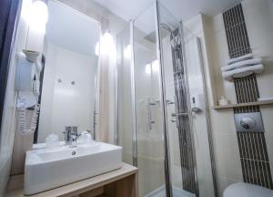 y baño blanco con lavabo y ducha. en Hôtel Inn Design Resto Novo Vannes en Theix
