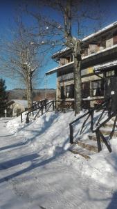 une maison dans la neige avec des bancs devant elle dans l'établissement B&B Bucaneve, à Abetone