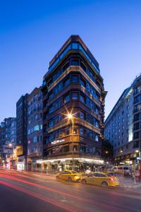 dos autos estacionados frente a un edificio alto en Taxim Suites Residences Istanbul en Estambul