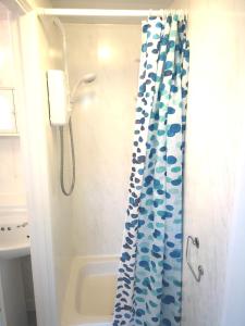 a bathroom with a shower with a blue shower curtain at Sandhaven Beach Chalets in South Shields