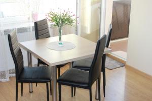 a dining room table with black chairs and a vase of flowers at Apartament Izabella in Suwałki