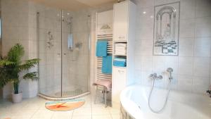 ein weißes Bad mit einer Badewanne und einer Dusche in der Unterkunft "Haus Ulla" in Bad Blankenburg