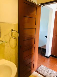 a bathroom door with a sink and a toilet at Hotel Hemadan in Bentota