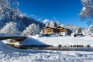 a lodge in the snow next to a river at Parkhotel Sonnenhof in Oberammergau