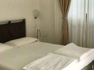 a bedroom with two beds with white sheets and a table at Appartamenti Gardastivo in Arco