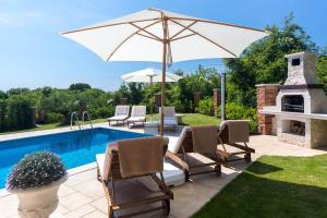 een patio met stoelen en een parasol naast een zwembad bij Luxury Villa Maša in Dobrinj