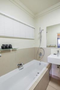 a bathroom with a tub, sink and mirror at Blue Waters Hotel in Durban