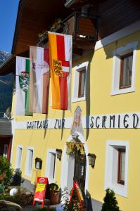 un edificio giallo con bandiere su un lato di Gasthof zur Schmiede a Berg im Drautal