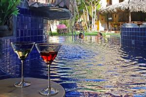 two glasses of wine sitting next to a swimming pool at Pousada Presidente Hotel in Canoa Quebrada