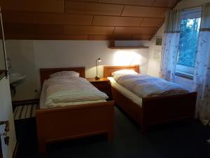 two twin beds in a room with a window at Gästehaus Hein in Emsbüren
