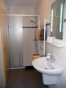 biała łazienka z umywalką i prysznicem w obiekcie Meeresblick Fehmarn Ferienhaus 42 w mieście Fehmarn
