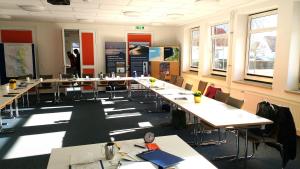 a classroom with long tables and chairs and windows at Jugendherberge Friedrichstadt in Friedrichstadt