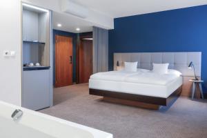 1 dormitorio con 1 cama blanca grande y bañera en Hotel Karpatia, en Humenné