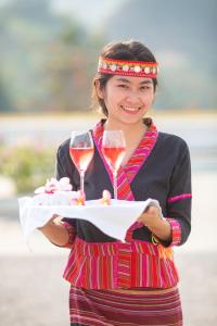 una mujer sosteniendo una bandeja con una copa de vino en Le Grand Pakbeng en Pakbeng
