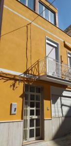 un edificio giallo con balcone e porta di Casa Vacanza Chiesa Madre a Canicattì