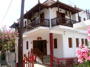 a white house with a red fence and pink flowers at Dafni Studios in Neo Klima