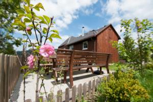欣特察爾滕的住宿－Ferienhaus Hinterzarten，木板凳,坐在木头建筑前