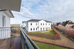 a white house on a balcony with a yard at Haus Strandperle in Börgerende-Rethwisch