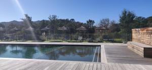 a swimming pool with chairs and umbrellas in a yard at Résidence Cala Sultana in Porto-Vecchio