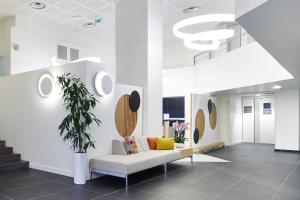 a waiting room with a couch and a plant at Hôtel Le Bayonne in Bayonne