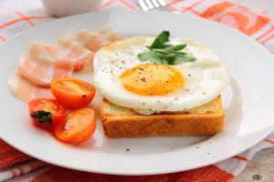 un plato con un huevo en un trozo de pan con tomates en Hotel Friends, en Volgograd