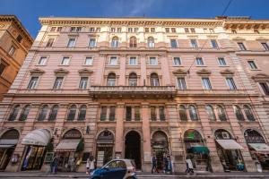 un grand bâtiment rose dans une rue de la ville dans l'établissement Four Rivers Suites, à Rome