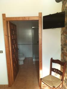 a bathroom with a toilet and a chair and a television at Casa Quiroga in Lamas