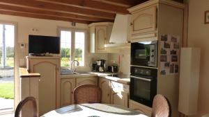 a kitchen with white cabinets and a table with chairs at l'Ecrin au coeur des vignes in Saint-Georges-sur-Cher