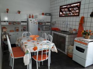 La cuisine est équipée d'une table, de chaises et d'un réfrigérateur. dans l'établissement Casa Completa na Praia, à Saquarema