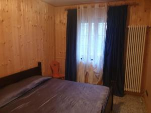 a bedroom with a bed and a window with curtains at Il Dehors in Champdepraz